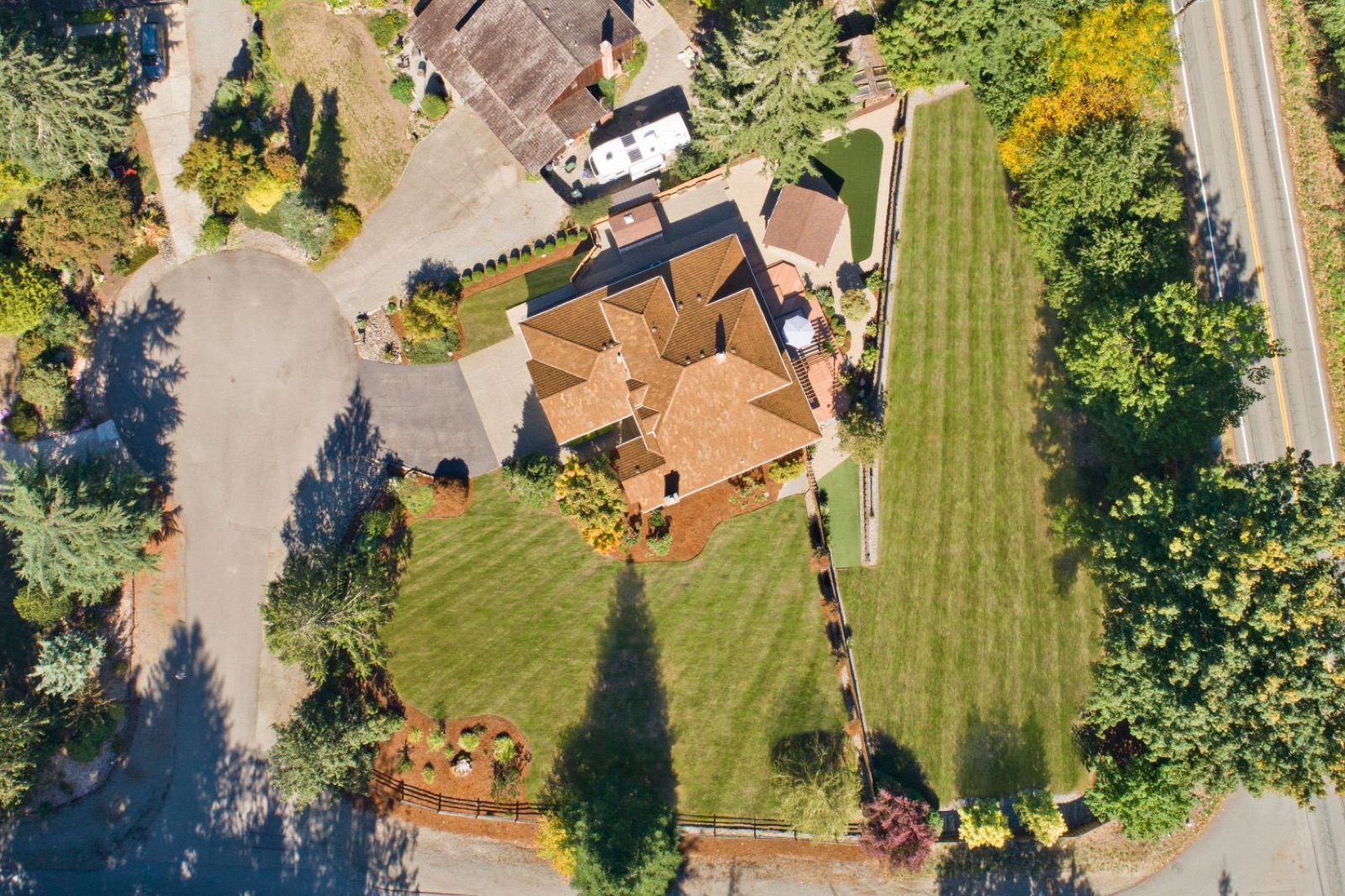 Aerial view of a home with a striped lawn, fresh bark beds, and a paver patio